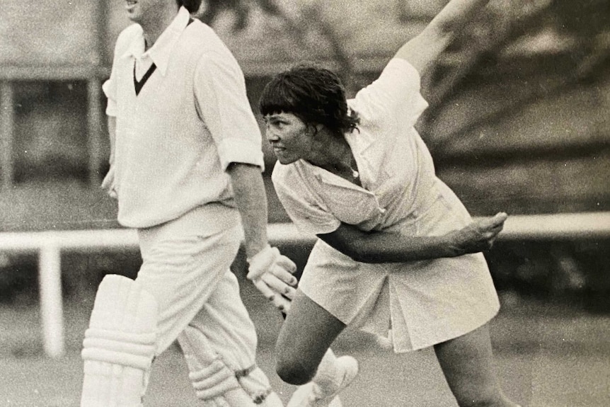 Raelee Thompson wears a white cricket skirt and long socks, with her arms aloft.