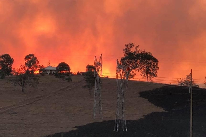 A house on a ridge with a horizon filled with fire.