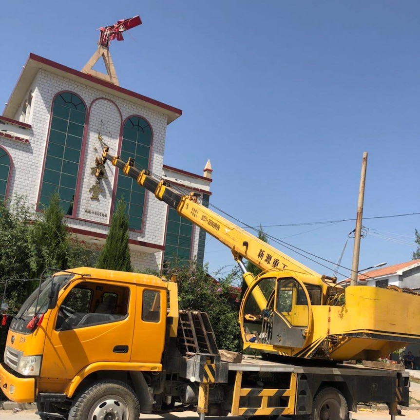 A truck with an outstretched crane on the back makes changes to a church's exterior.
