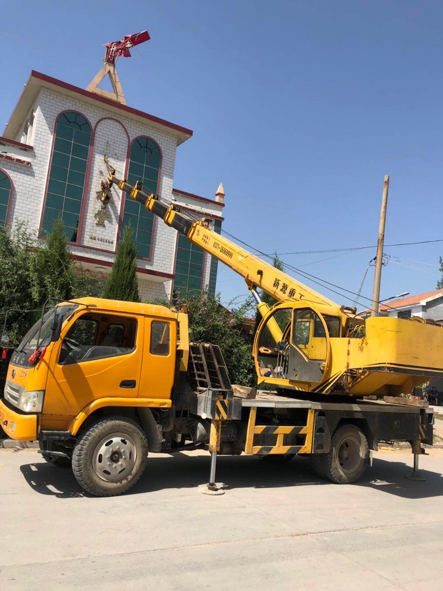 A truck with an outstretched crane on the back makes changes to a church's exterior.