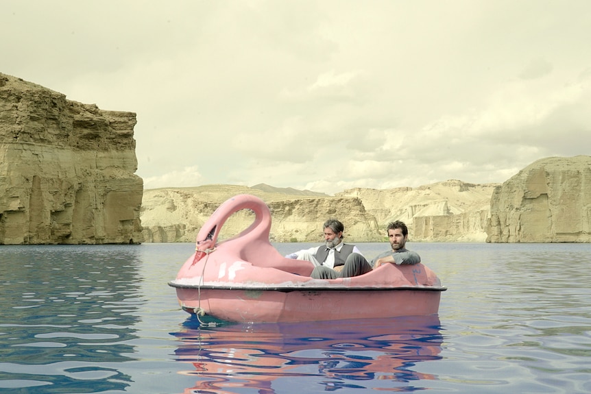 Two men in a pink boat shaped like a swan, in a lake in Afghanistan.