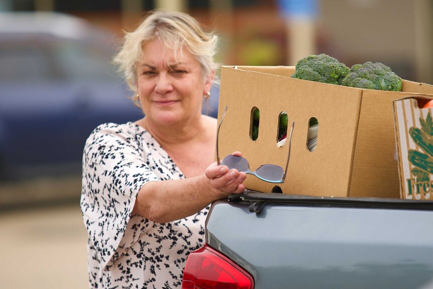 Robyn Sturgess standing beside a ute with a box of green vegetables.