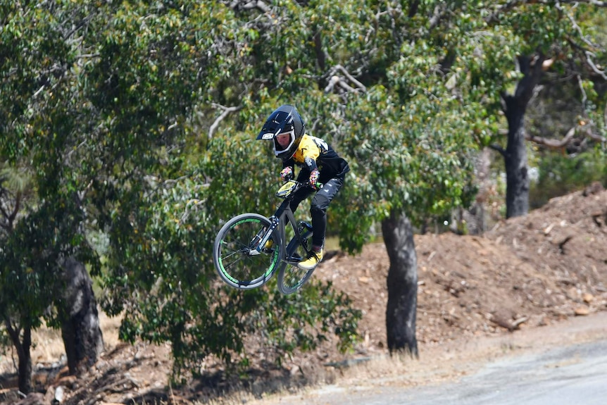 a young boy on a bike doing a jumping stunt