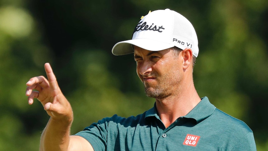 Adam Scott squints as he lines up a putt.