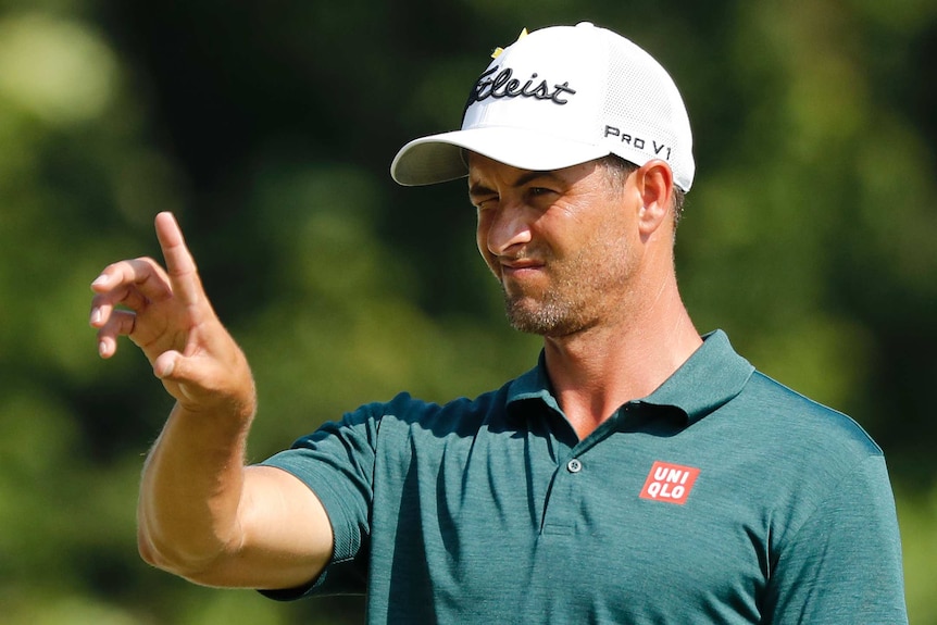 Adam Scott squints as he lines up a putt.