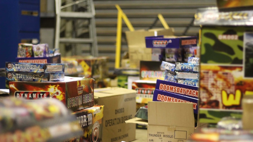 Cardboard boxes full of fireworks lay open and stacked on the floor of a warehouse in Darwin.