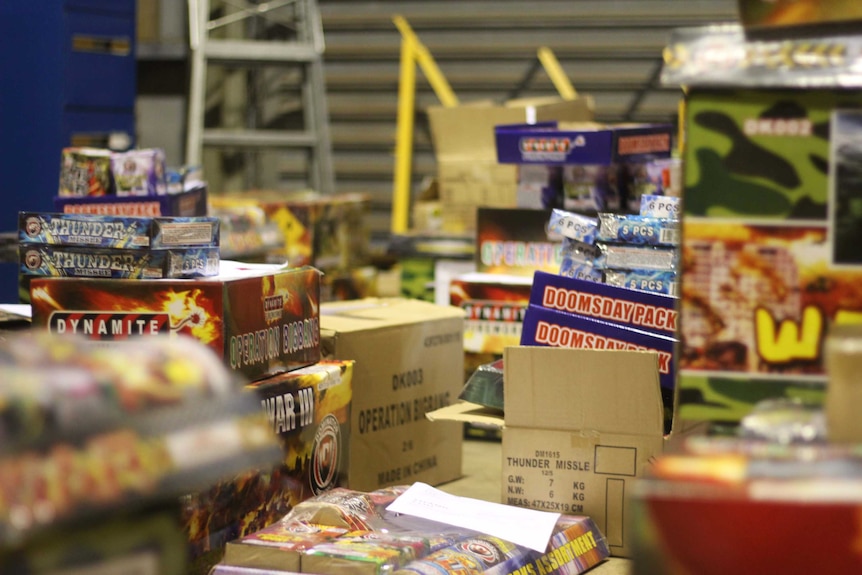 Cardboard boxes full of fireworks lay open and stacked on the floor of a warehouse in Darwin.