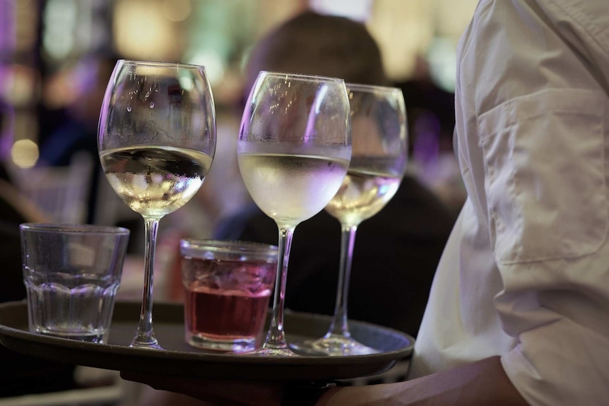 Waiter carrying tray of drinks.