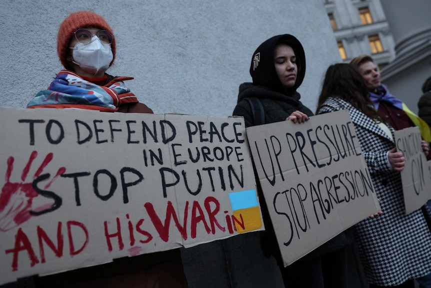 Activists hold banners in Kyiv, one reading 'to defend peace in Europe stop Putin and his war in Ukraine'