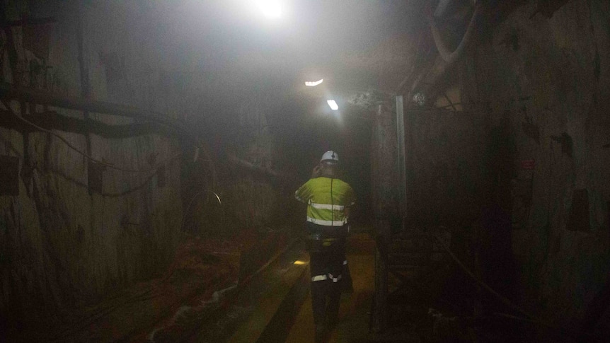 Man walking along mine tunnel.