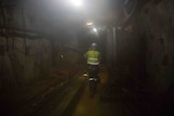 Man walking along mine tunnel.
