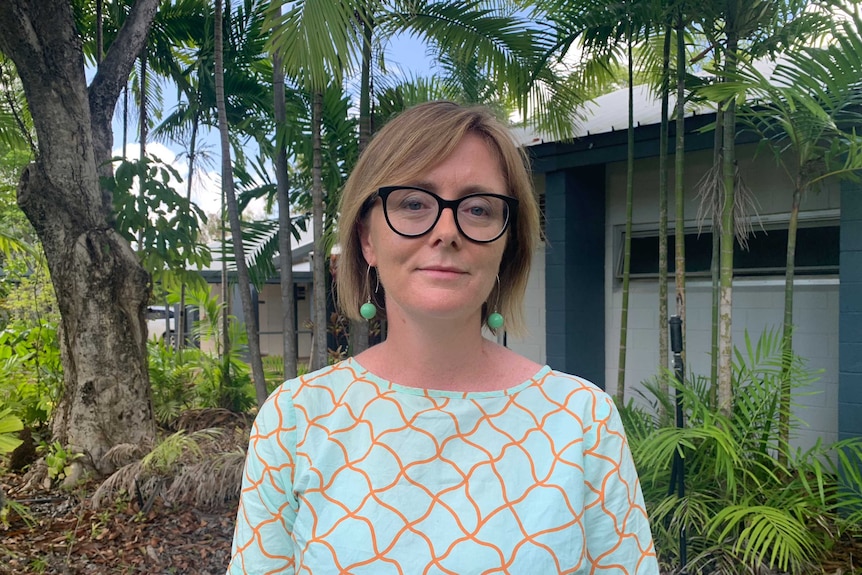 A woman wearing glasses and a light blue top.