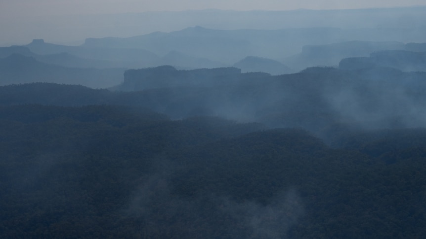 Peaks and cliffs of Carnarvon Gorge covered in white/grey smoke.