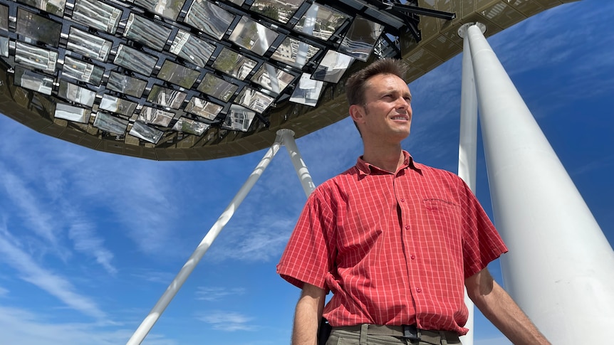 a man on op of a building underneath a heliostat