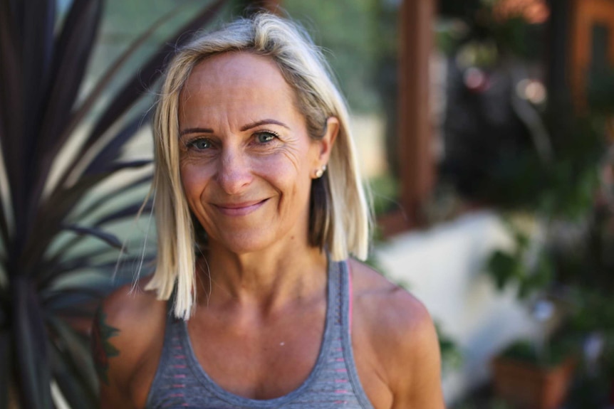 A woman in a grey Lorna Jane singlet top photographed in her garden.