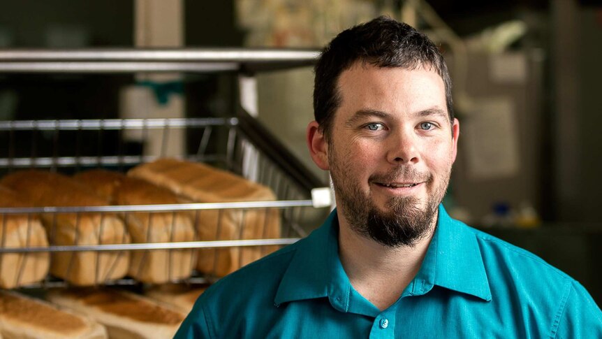 Man stands in front of racks of bread loaves