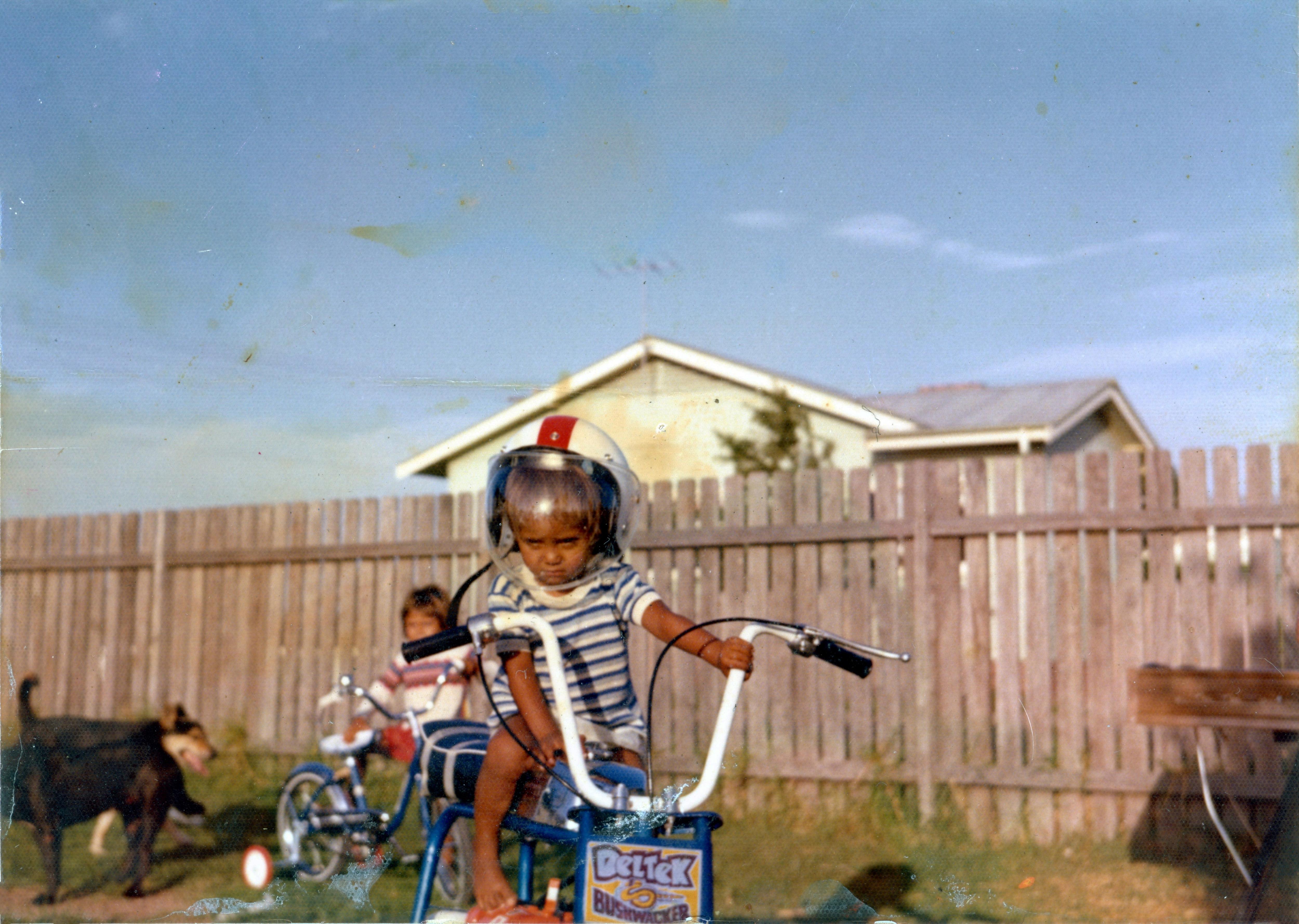 A young boy rides a bicycle wearing an astronaut's helmet. 