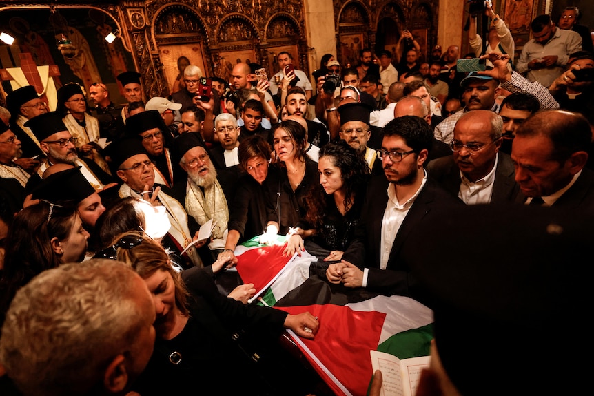 Family and friends mourn around a coffin inside a packed church.