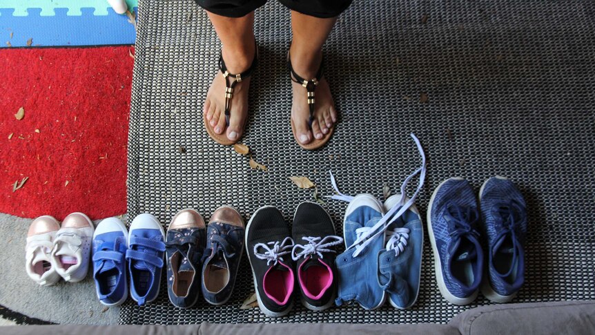 Six pairs of shoes are lined up next to each other with grandma's feet facing them
