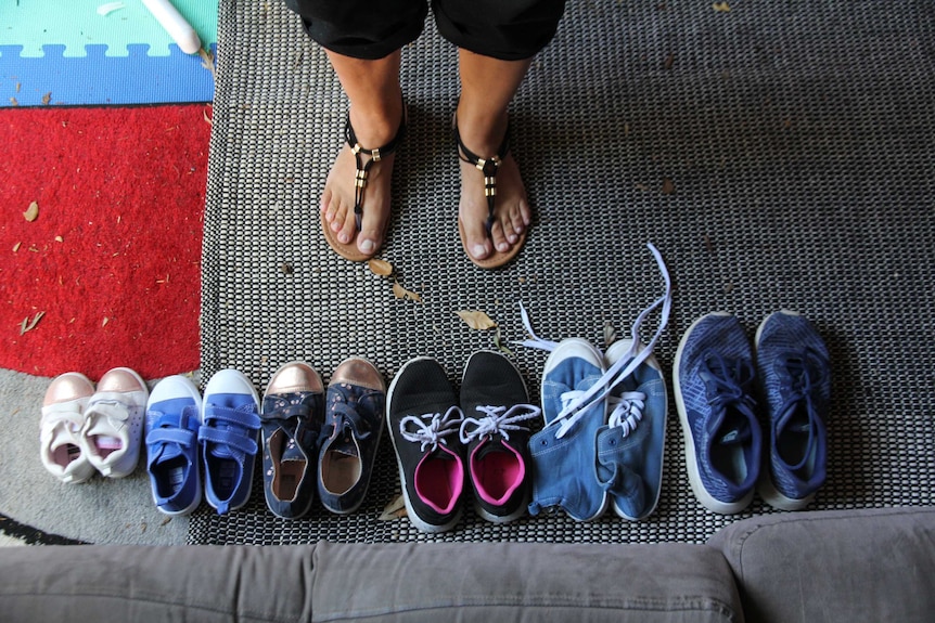 Six pairs of shoes are lined up next to each other with grandma's feet facing them