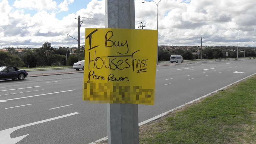 Sign on a light post in Perth saying 'I buy houses fast, phone Rowan'