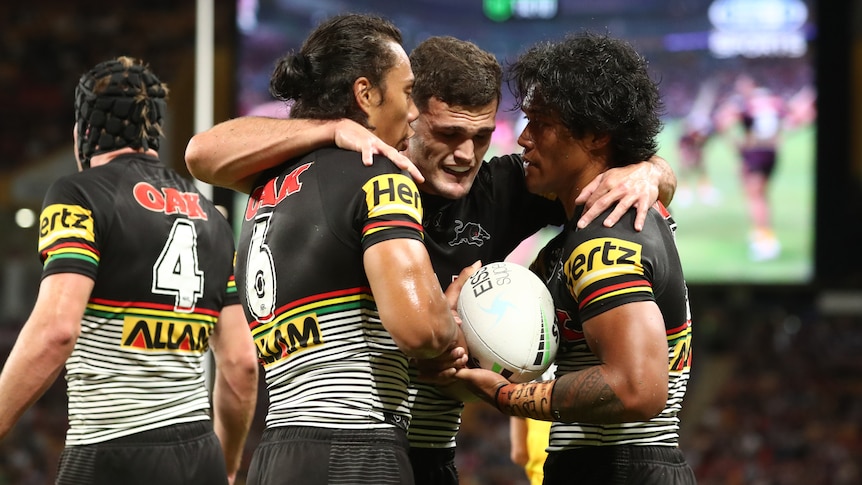 Rugby league players hugging in celebration after scoring a try during a match.