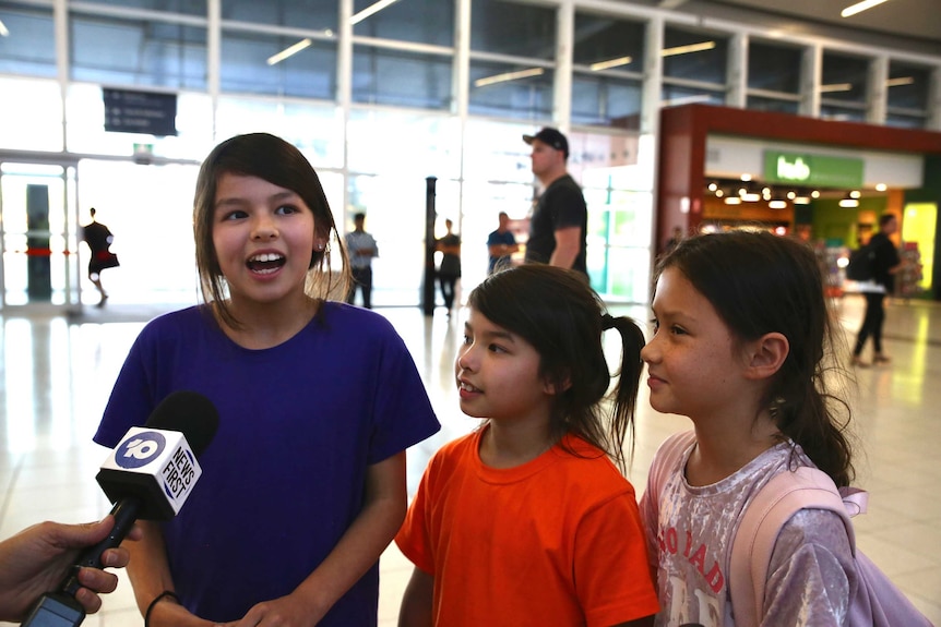 Three children are interviewed, one is speaking into a microphone.