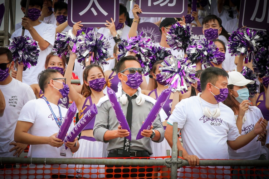 A group of people cheered, holding purple balloons and placards of "Suncity Group".