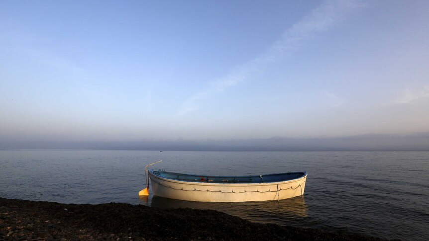 A wooden boat abandoned at a beach on the Greek island of Lesbos