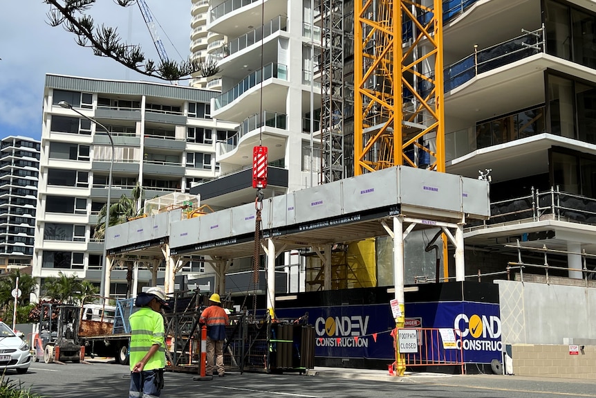 A construction site on a city block manned by workers in high-vis.