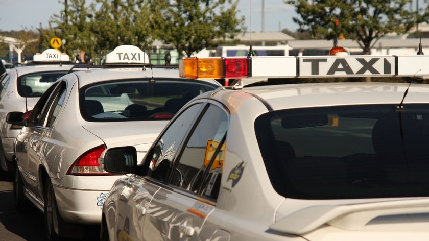 Three taxis wait at a taxi rank