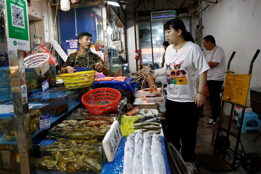 海产摊前，一位女士在购买龙虾。
