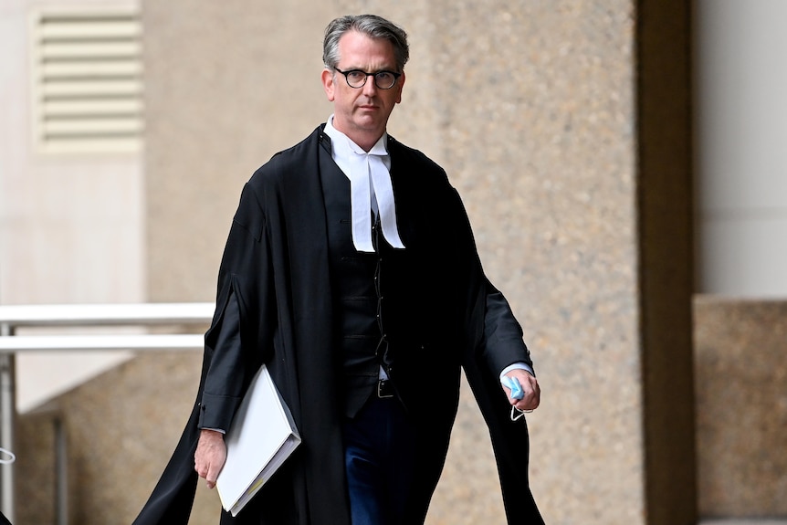 a man wearing glasses, a judge walking outside a court room