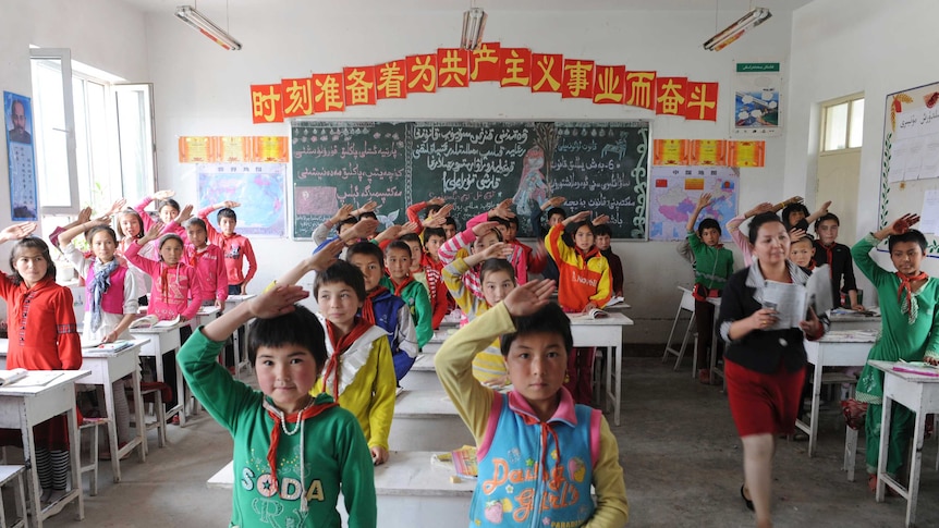 Students from ethnic minorities give the Young Pioneer's salute to their teacher in a classroom.