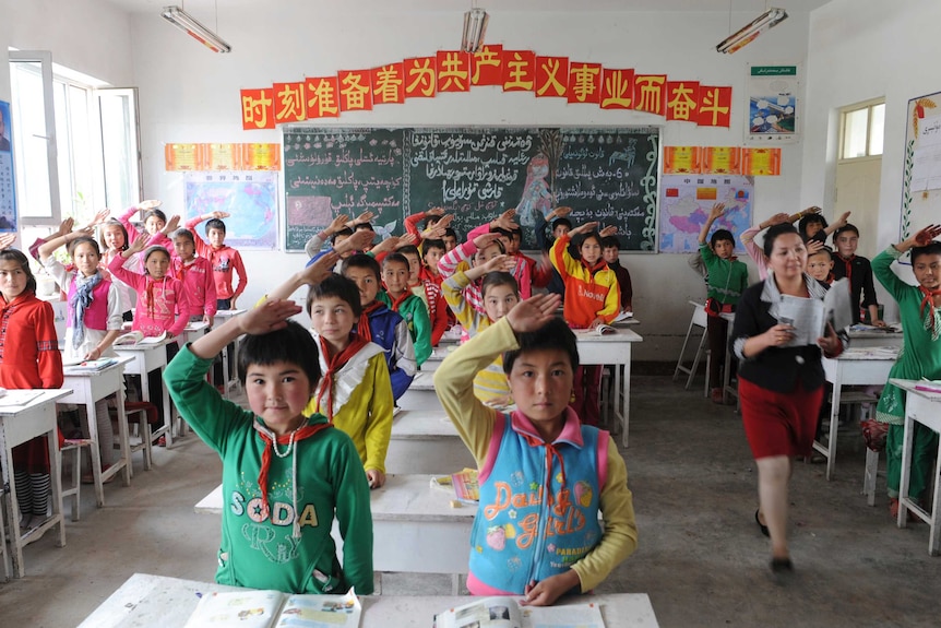 Students from ethnic minorities give the Young Pioneer's salute to their teacher in a classroom.