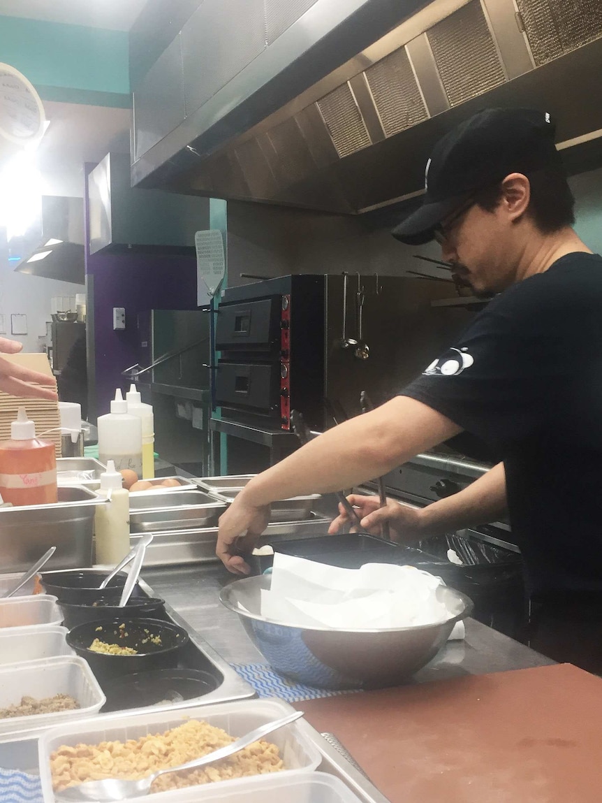 A man prepares food in a kitchen which provides food for delivery app Deliveroo.