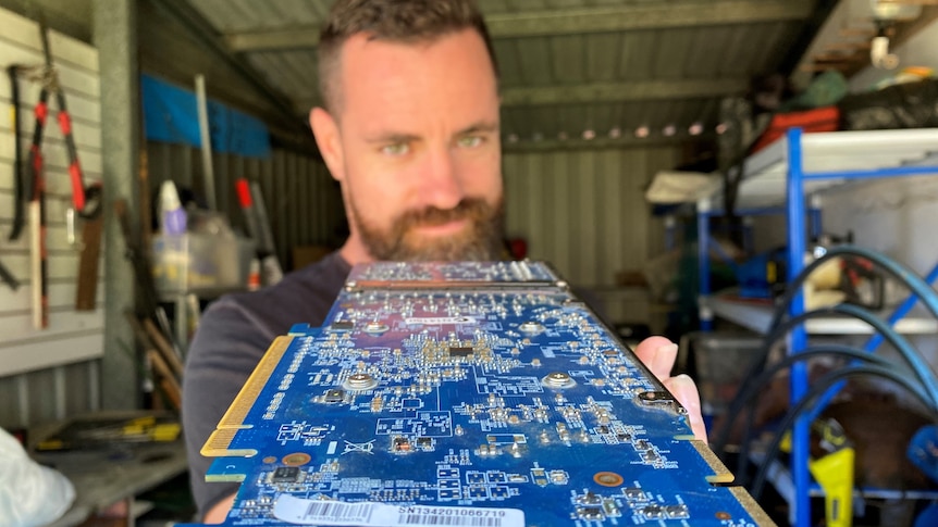 Joe Bridge holding a computer expansion card towards the camera.