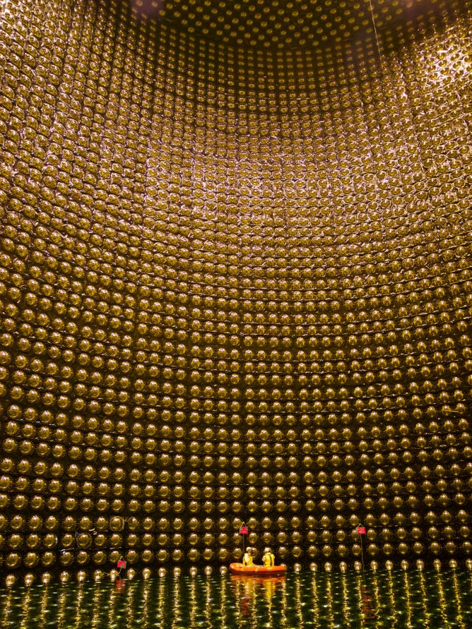 Tiny boat at the bottom of enormous circular wall of golden light bulbs.
