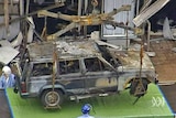 Investigators examine the burnt-out remains of a car from the Glasgow Airport attack.