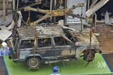 Investigators examine the burnt-out remains of a car from the Glasgow Airport attack.