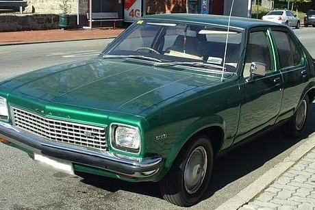 a dark green vintage car on a street