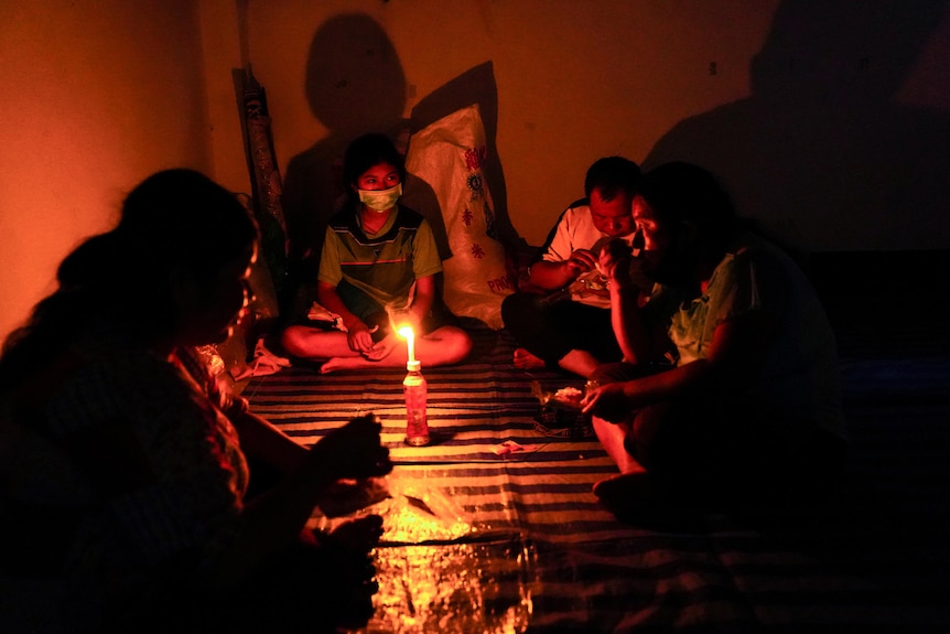 Silhouettes of people sitting by candlelight.