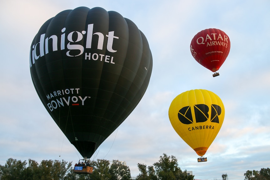 Three hot air balloons flying in the air. 