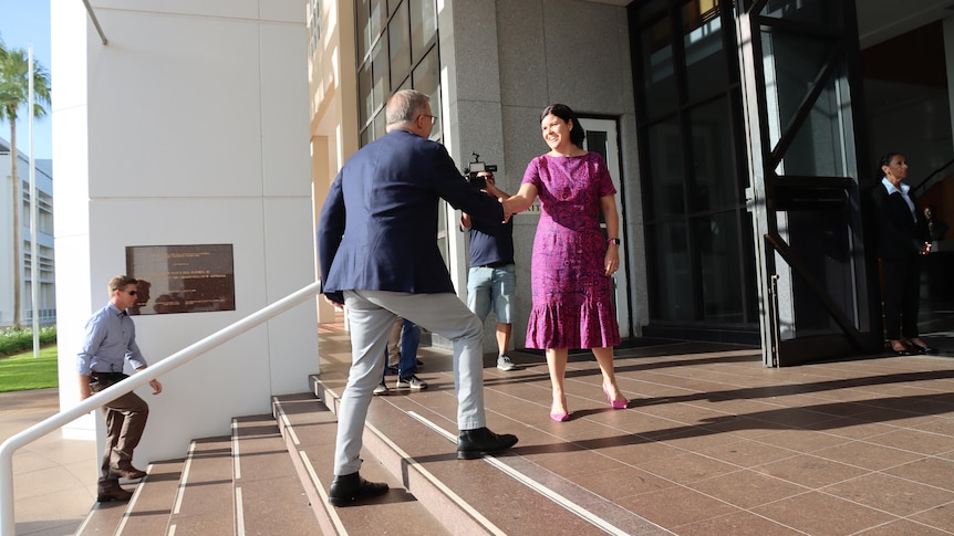 Anthony Albanese walks up a set to stairs and shakes hands with Natasha Fyles. 