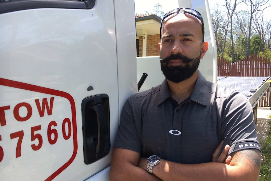 Ricky Singh stands next to his tow truck