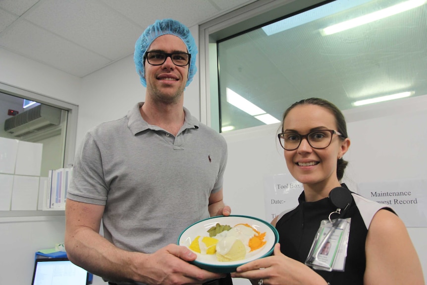Two people hold up a plate of pureed moulded food