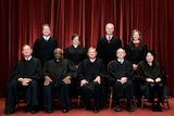 Nine US Supreme Court justices pose for a group photo in black robes. Five are sitting down, four are standing.