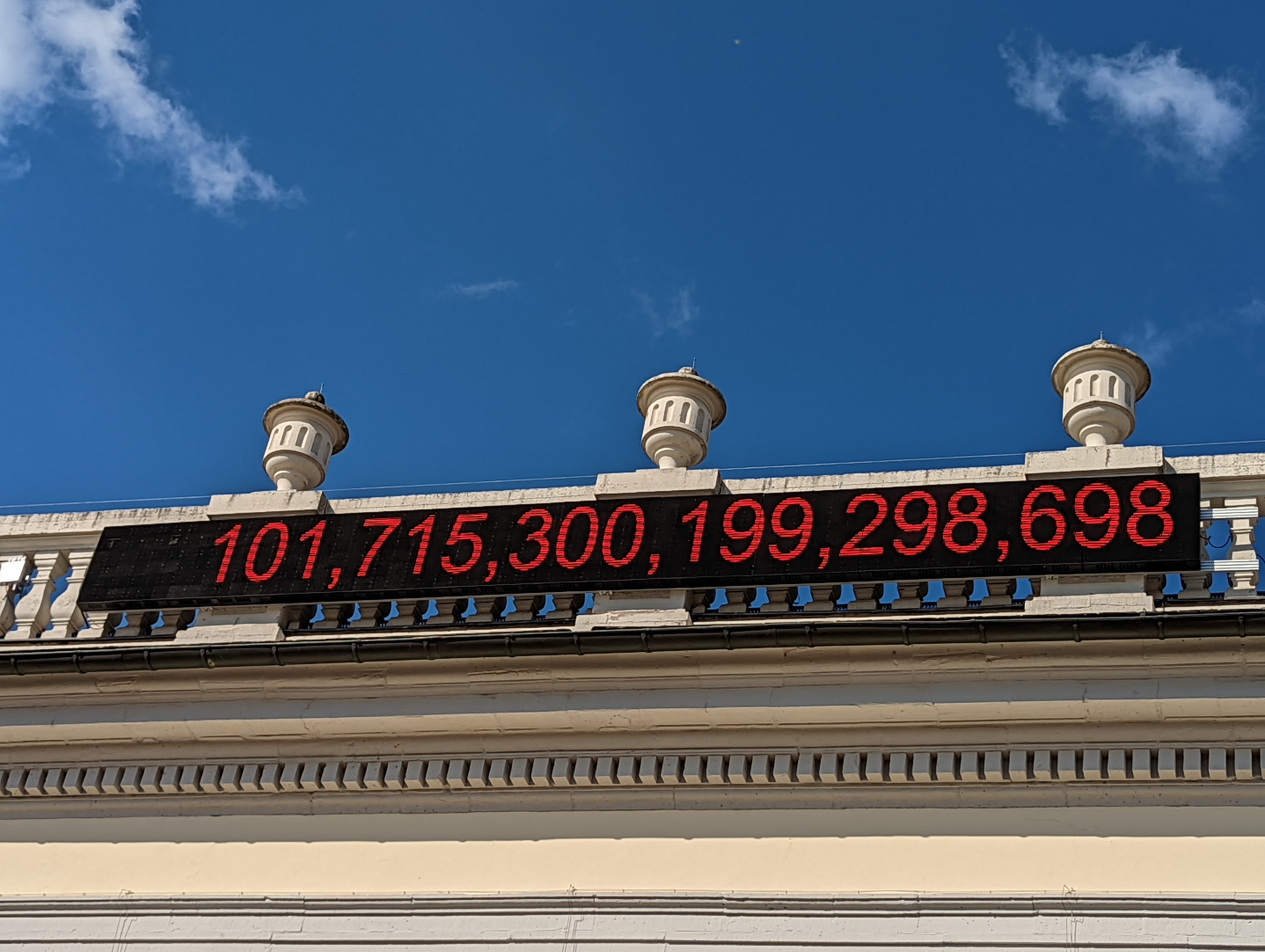 A large digital ticker shows the number 101,715,300,199,298,698 in red over a black background installed on a gallery rooftop.