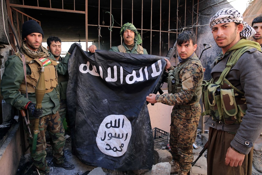 Kurdish and Yazidi forces hold an Islamic State flag after retaking the Yazidi town of Sinjar