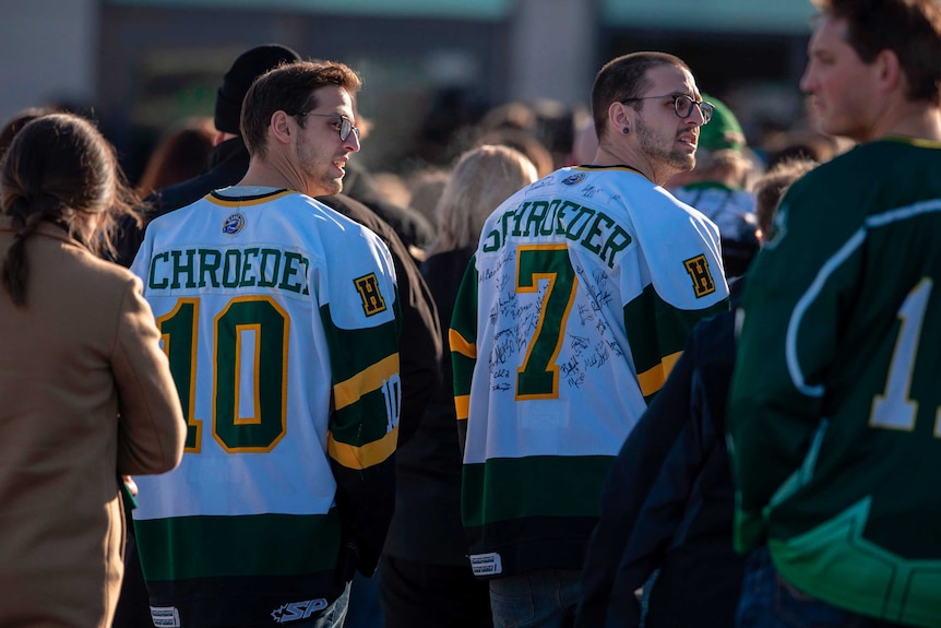 A group of people is seen, two of them wearing the hockey team's jerseys.